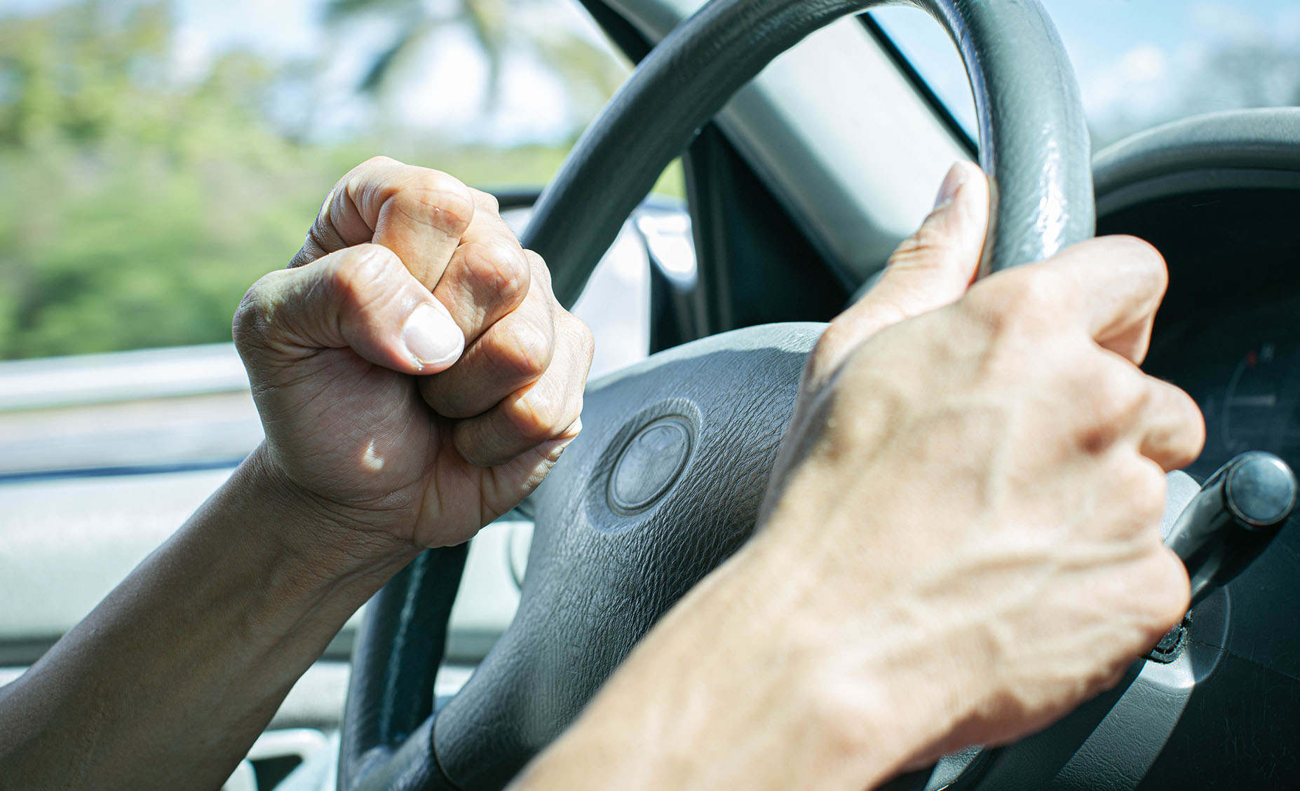 A person holding the steering wheel and honking.